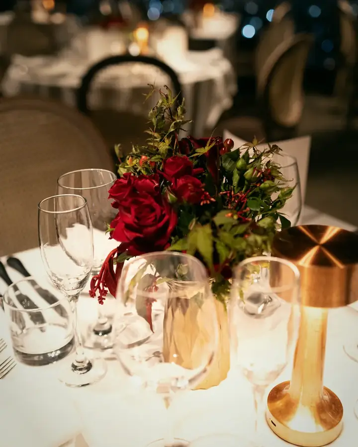 Gedeckter Tisch mit roten Rosen, Kristallgläsern und goldener Leuchte bei Nacht im Terraço Itália